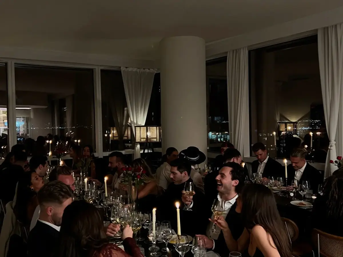 Members at a long dinner in a candlelit hall