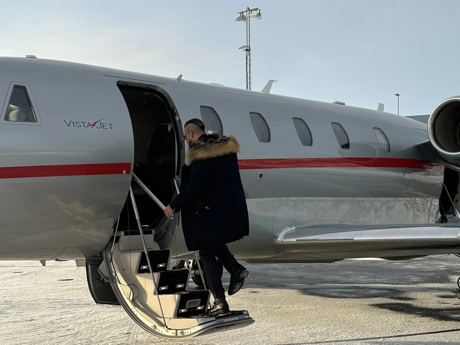 An executive boarding a private jet on a winter runway