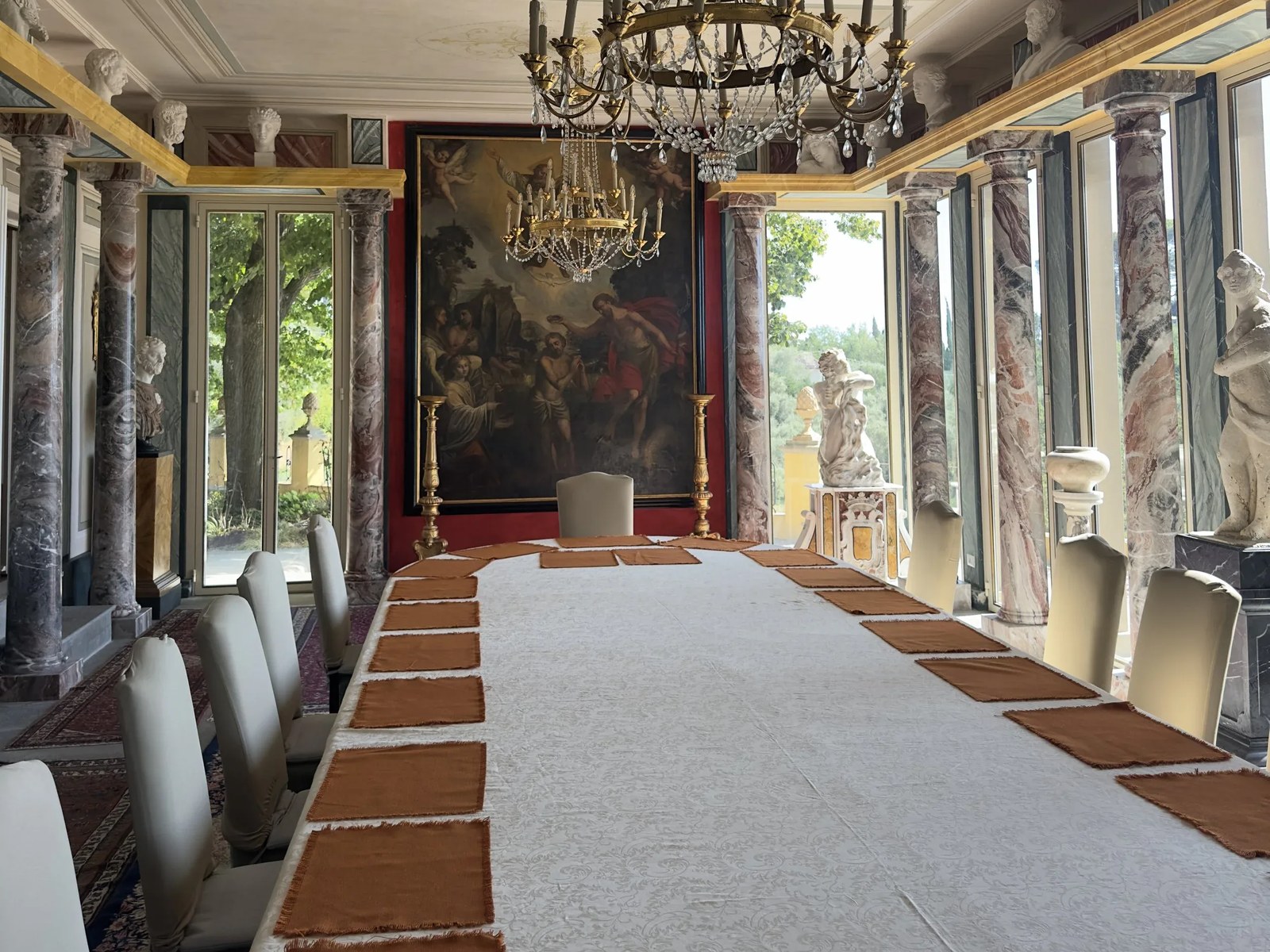 A long dinner table set in a frescoed hall