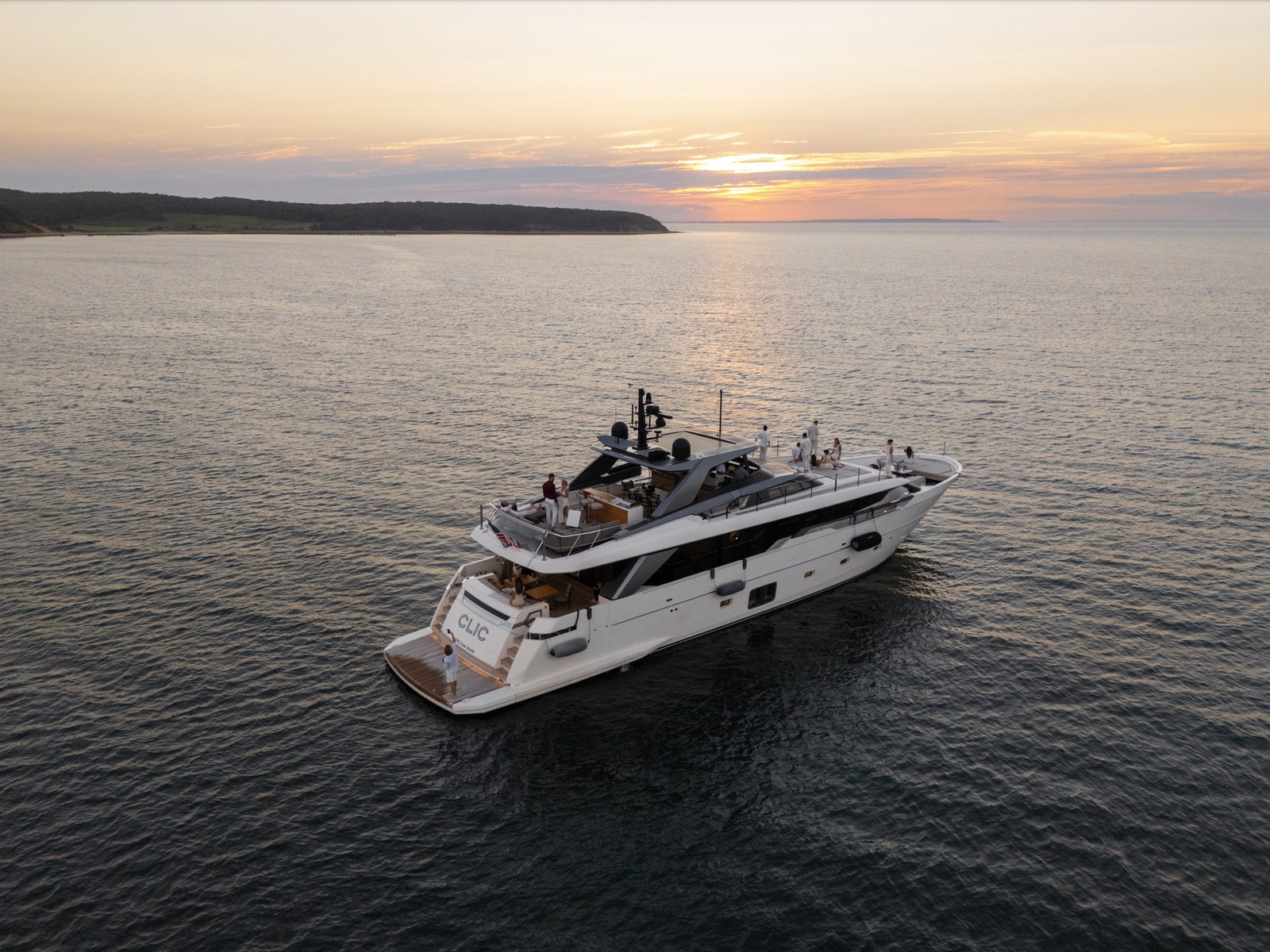 A superyacht cruising at sunset with guests on deck